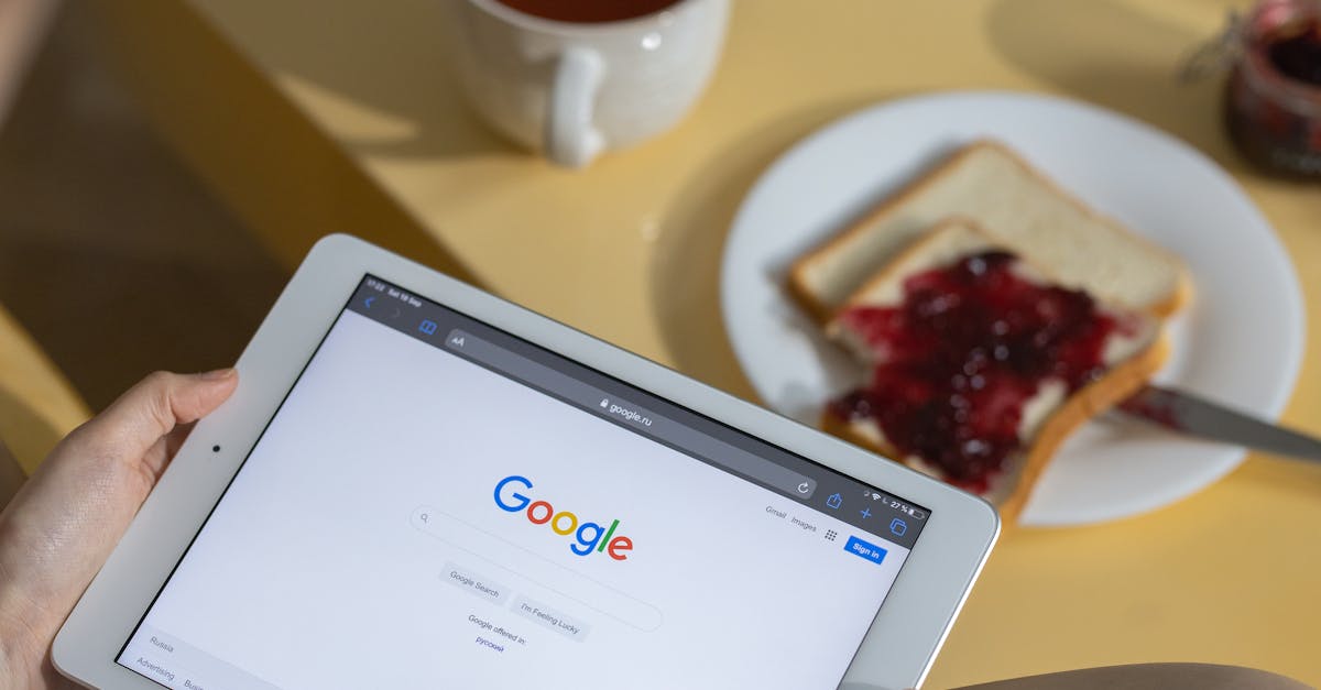 Person using a tablet with Google search open while having breakfast with toast and tea.